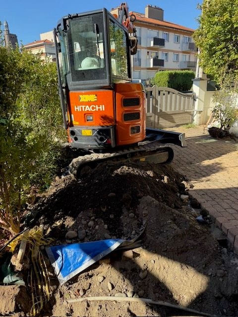 Mini-pelle dans le jardin d’une maison à Clermont-Ferrand, terres de la tranchée de raccordement