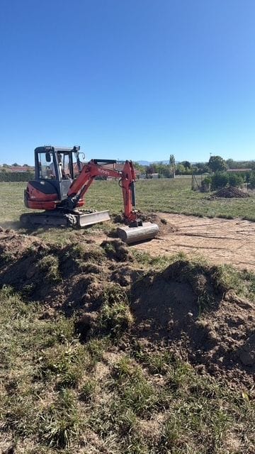 Mini-pelle décapant la terre végétale d’un terrain à Maringues, avant la construction d’une villa